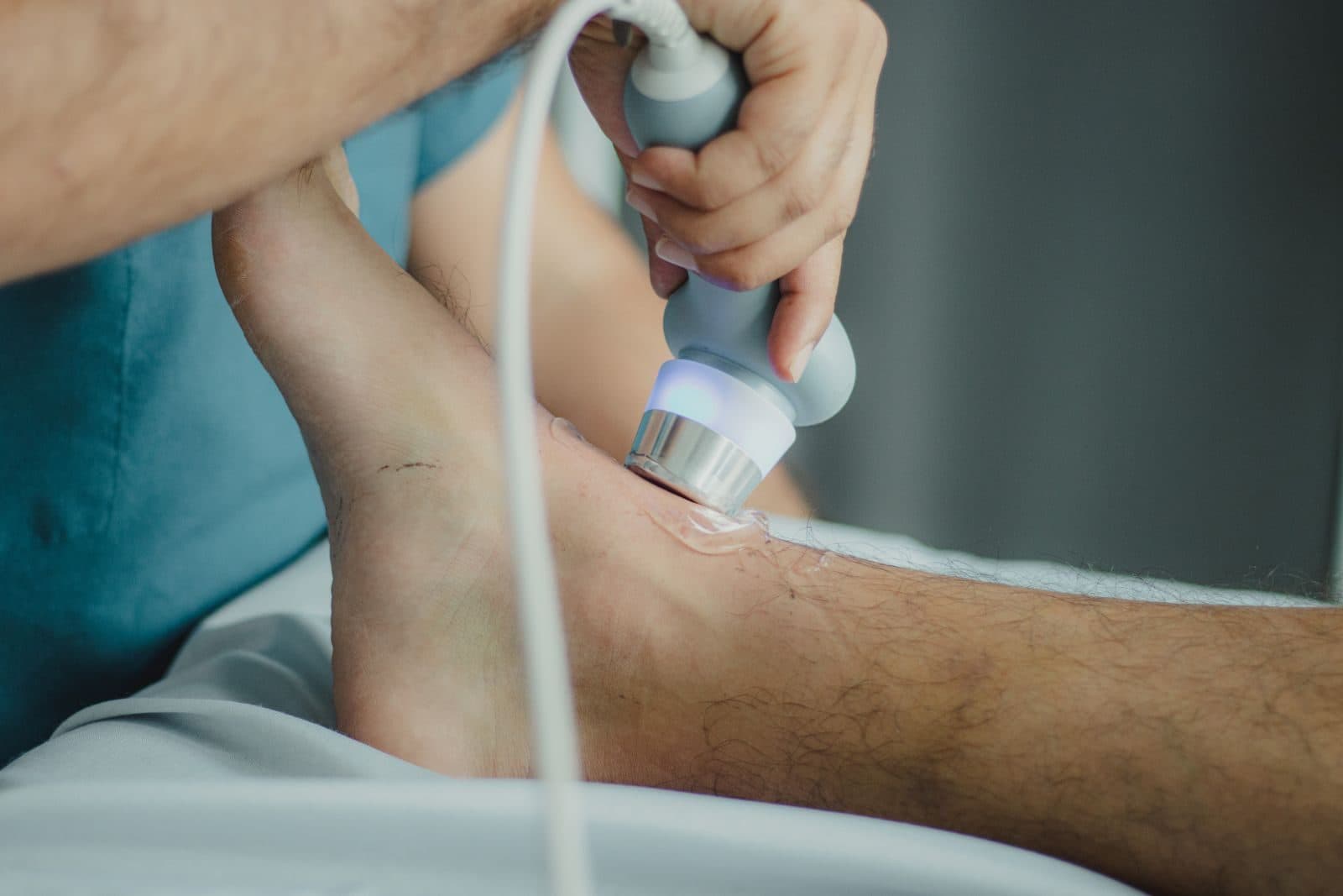 Clinician applying a therapy device to a patient's knee in a medical clinic