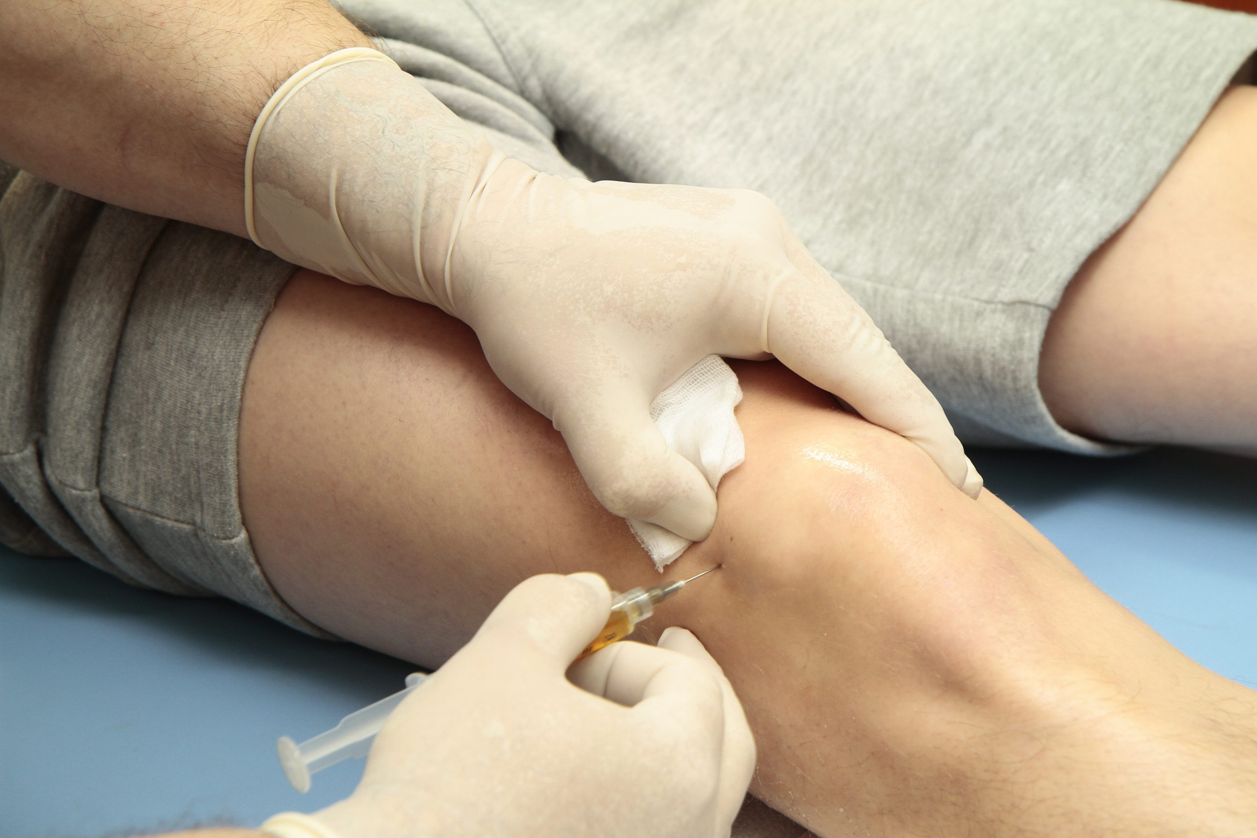 A clinician administering a regenerative injection at a patient's knee